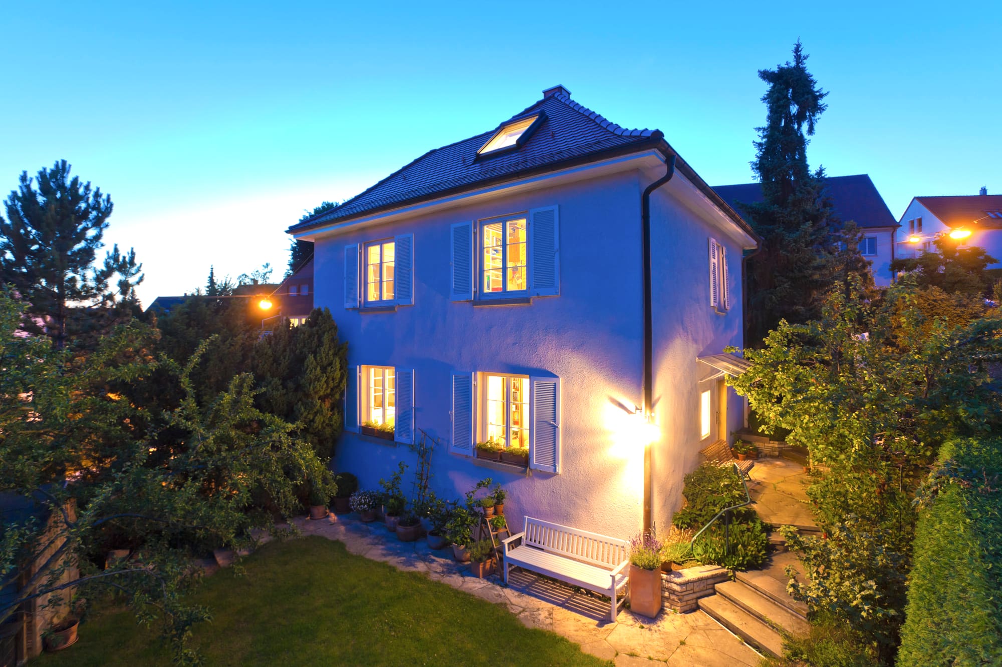 Einfamilienhaus zur blauen Stunde mit beleuchteten Fenstern und Garten