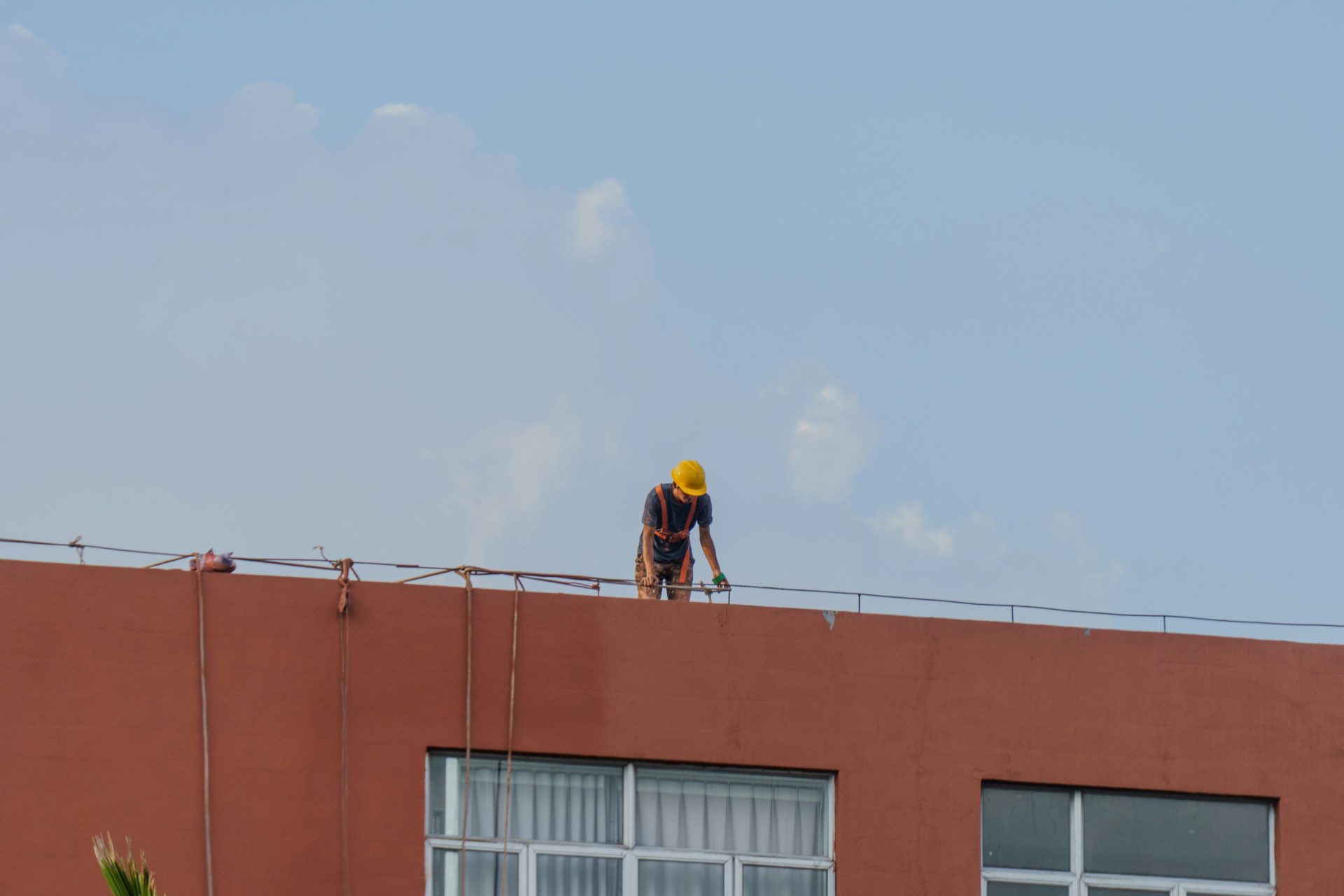 Arbeiter mit gelbem Schutzhelm auf einem Gebäudedach
